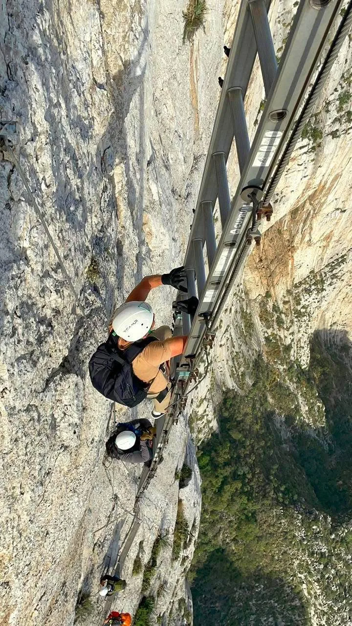 Ascenso técnico en una pared de roca con escalera y línea de seguridad